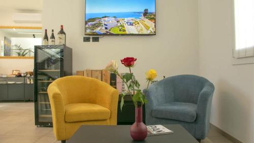 two chairs and a table with a tv on the wall at Dimora 5 Sensi in Pozzuolo del Friuli