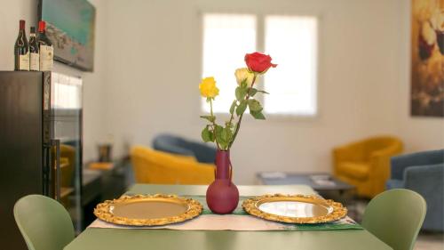 a table with two plates and a vase with a flower at Dimora 5 Sensi in Pozzuolo del Friuli