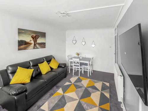 a living room with a black leather couch and yellow pillows at Modern 2 BR ground floor apartment with parking and garden in Belvedere