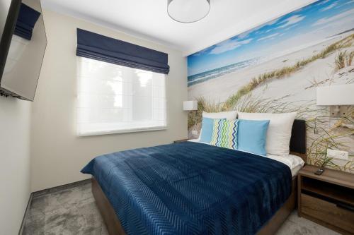 a bedroom with a bed and a painting of a beach at A.S.Apartamenty Bożena Bocian in Niechorze
