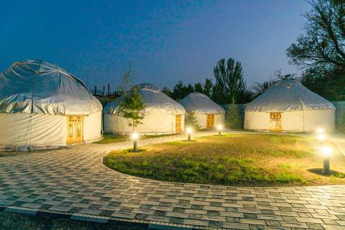 a group of four tents with lights in the grass at Komay Yurt Camp Karakol in Karakol