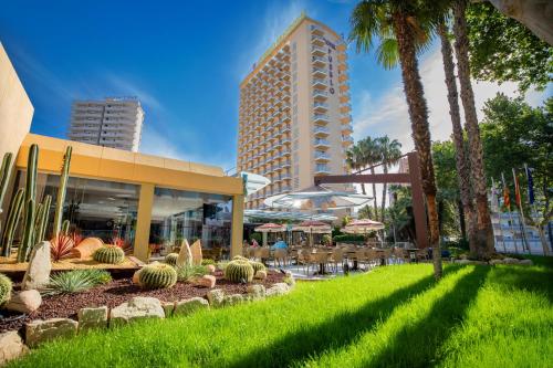 a resort with tables and chairs and palm trees at Hotel Servigroup Pueblo Benidorm in Benidorm