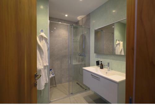 a bathroom with a glass shower with a sink and a sink at Gümüşlük Infinity Villa Seaview, Pool & Sauna in Bodrum City