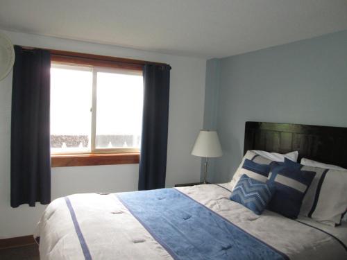 a bedroom with a bed with blue pillows and a window at Mittersill Alpine Resort in Franconia