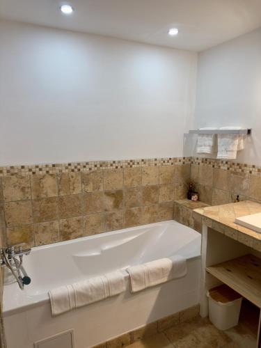 a white bath tub in a bathroom with a sink at Le Mas des Eglantiers in Propiac
