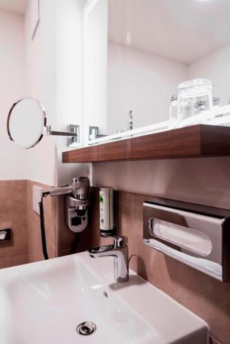 a bathroom with a white sink and a mirror at DORMERO JeHo Graz Airport in Feldkirchen bei Graz