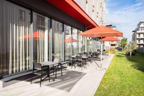 a group of tables and chairs with umbrellas outside a building at DORMERO JeHo Graz Airport in Feldkirchen bei Graz