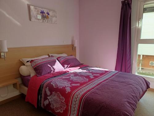 a bedroom with a bed with purple sheets and a window at Cami del Canigou in Vernet-les-Bains