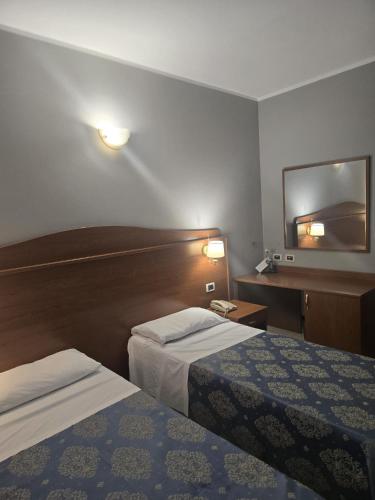 una camera d'albergo con due letti e uno specchio di Hotel Rigolfo a Moncalieri