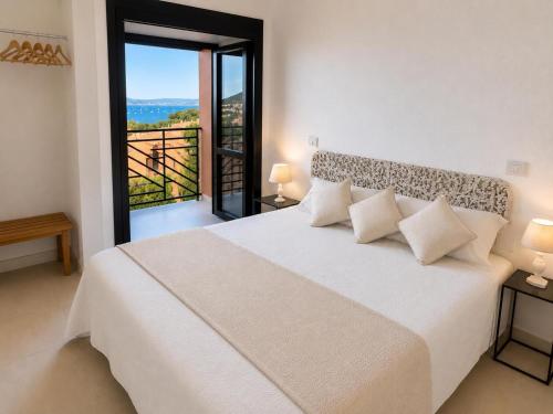 a white bedroom with a large bed and a balcony at Villasimius Il patio sul porto in Villasimius