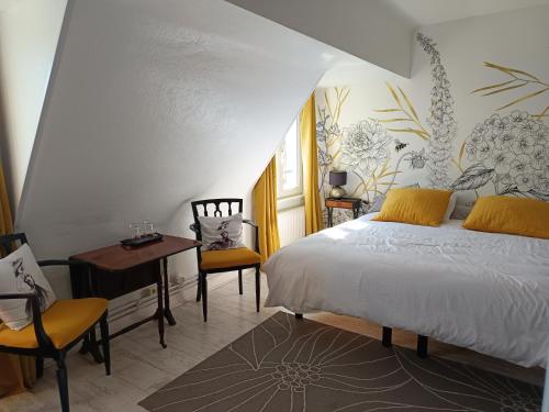 a bedroom with a bed and a table and chairs at La Coccinelle Des Caps in Ambleteuse