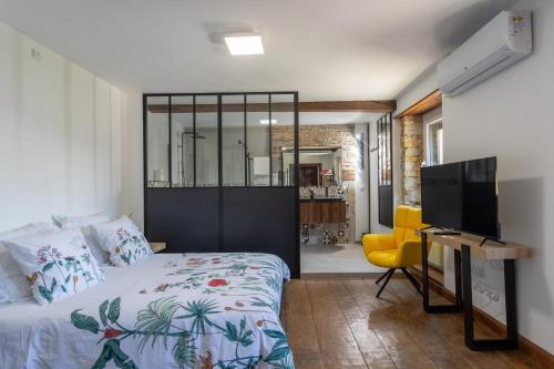 a bedroom with a bed and a desk and a television at Domaine Cherps Spa - Sérénité in Vielleségure
