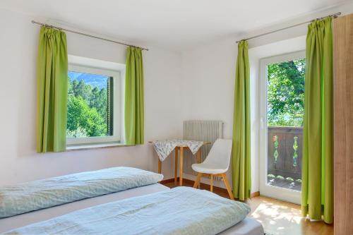 a bedroom with green curtains and a table and a bed at Rienznerhof Natureplace in Montagna