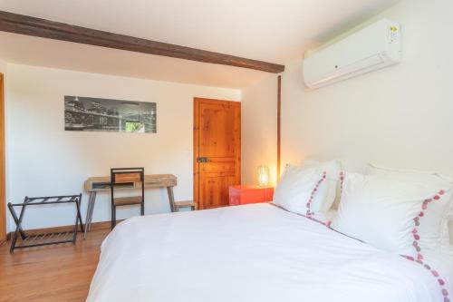 a bedroom with a white bed and a desk at Domaine Cherps Spa - Zen in Vielleségure