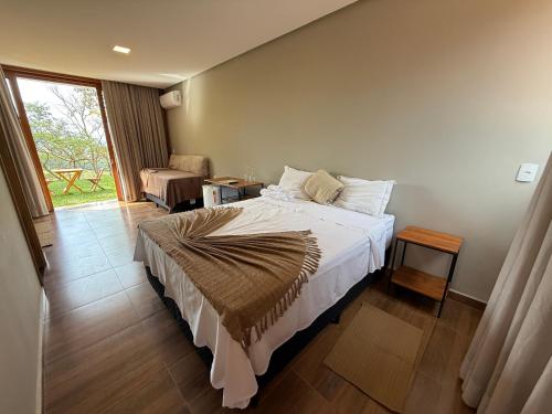 a bedroom with a bed and a chair and a window at Pousada Carraro in Delfinópolis
