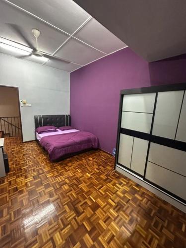 a bedroom with a purple bed and a wooden floor at Kapar Cozy Homestay in Kapar