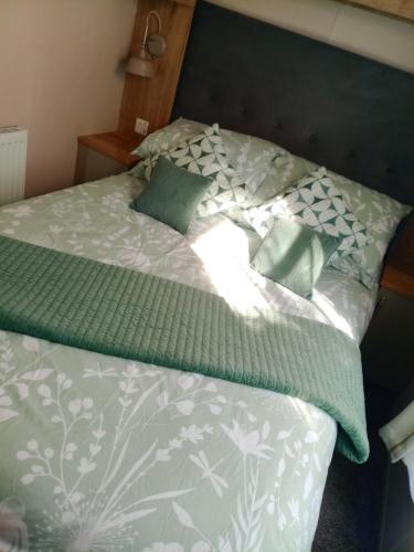 a bed with green and white sheets and pillows at 75 Orchard Mount, 3 bed luxury caravan Skirlington- sleeps 6 in Hornsea