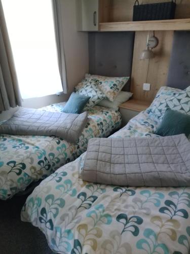 a room with three beds with pillows on them at 75 Orchard Mount, 3 bed luxury caravan Skirlington- sleeps 6 in Hornsea