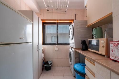 a small kitchen with a washer and dryer in it at Guest House Da Mata in Póvoa de Varzim