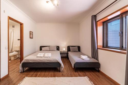 a bedroom with two beds and a window at Guest House Da Mata in Póvoa de Varzim