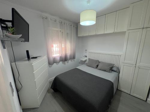 a bedroom with a bed and a tv and white cabinets at Estudio Bajamar in Torre del Mar