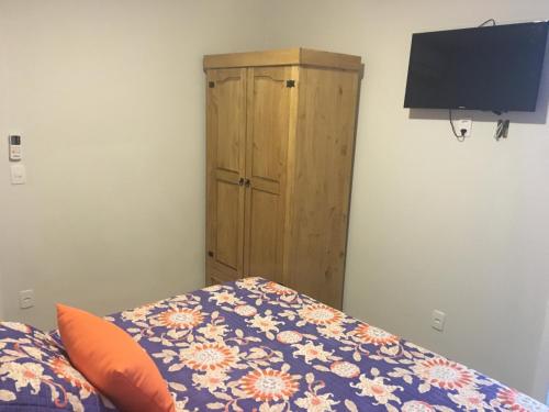 a bedroom with a bed and a wooden cabinet at Hospedaria Conceitual in Florianópolis