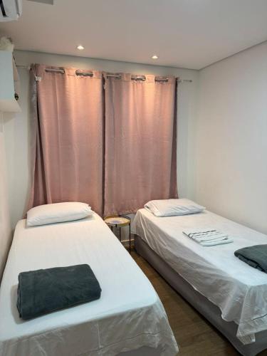 two beds sitting next to each other in a room at Apartamento Garden com churrasqueira área Gourmet in Bauru