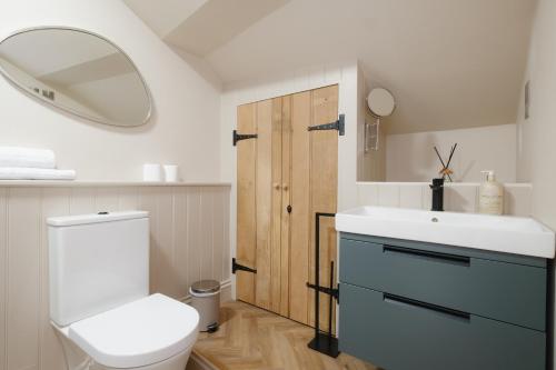 a bathroom with a toilet and a sink and a mirror at Lowcross House in Whitchurch
