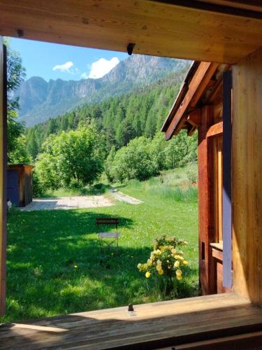 a window view of a yard with a bench in the grass at gîte l'écureuil roux in LʼArgentière-la-Bessée