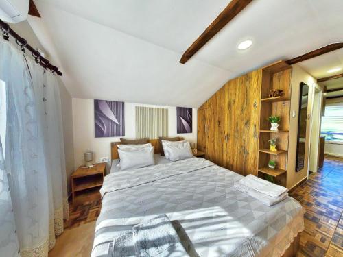 a bedroom with a large bed and wooden walls at Apartman Dve lipe in Palić