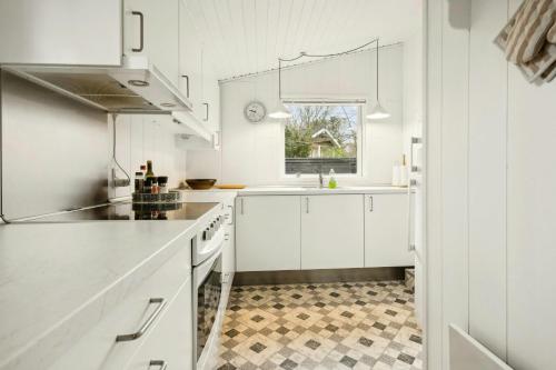 a kitchen with white cabinets and a checkered floor at Cottage Near Forest And Beach in Glesborg