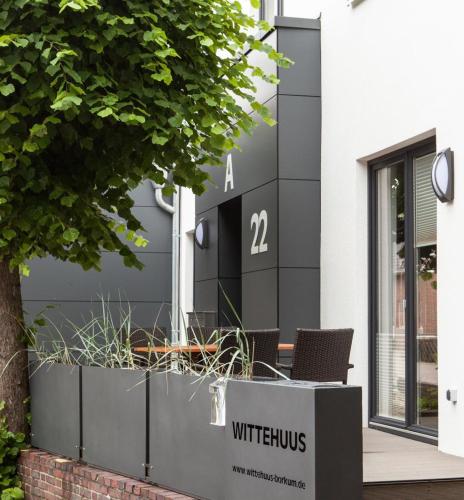 a black and white building with two chairs in front at Wittehuus Wohnung 1 in Borkum