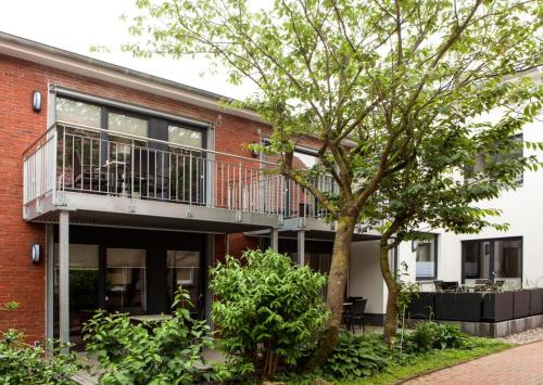 a brick building with a balcony and a tree at Wittehuus Wohnung 1 in Borkum