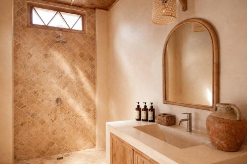 a bathroom with a sink and a shower with a mirror at Villa Kampung in Gili Islands