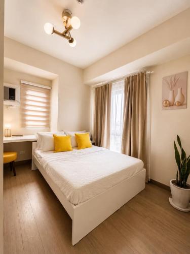a bedroom with a bed with yellow pillows and a desk at Oasis 8 in Bacolod
