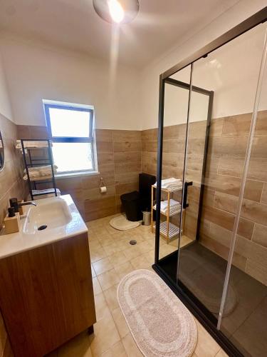 a bathroom with a sink and a glass shower at O Jardim Mágico in Teixoso