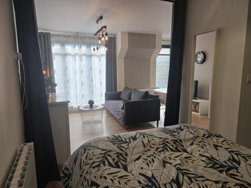 a bedroom with a bed and a living room with a couch at 1 Le Cocon Mosaïque Centre-ville in Ernée