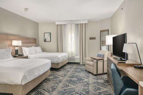 a hotel room with two beds and a flat screen tv at Candlewood Suites Longview by IHG in Longview