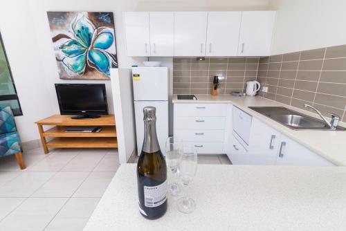 a bottle of wine sitting on a counter with two wine glasses at Beach Club Resort Mooloolaba in Mooloolaba