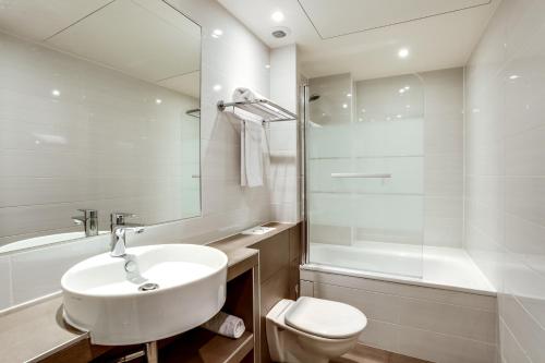 a white bathroom with a sink and a toilet at Hotel d'Amiens in Paris