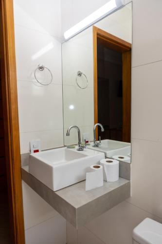 a white bathroom with a sink and a mirror at Hotel Descalvado in Descalvado