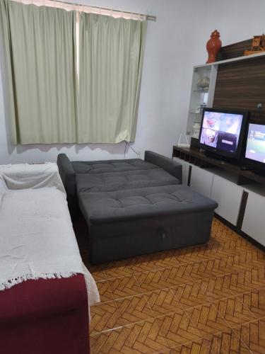a living room with a bed and a flat screen tv at Casa ampla in Muriaé
