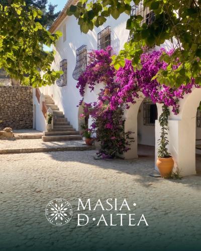 a street with purple flowers in front of a white building at Hotel Masía de Altea in Altea