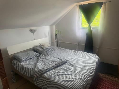 a bedroom with a bed with striped sheets and a window at Horse Garden in Valea Groşilor