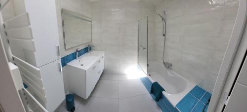 a white bathroom with a sink and a shower at Maison Fabien in Surzur