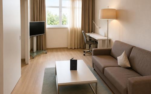 a living room with a couch and a table at DORMERO Hotel Fürth in Fürth