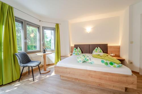 a bedroom with a bed with a chair and windows at Residence Passerhaus in Schenna