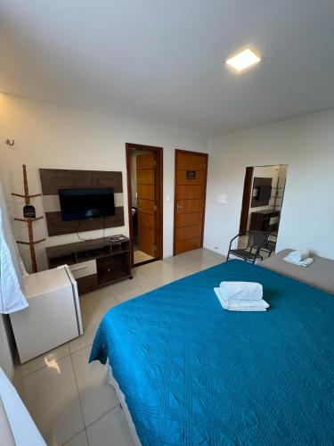 a bedroom with a blue bed and a flat screen tv at Hotel Califórnia in Canindé