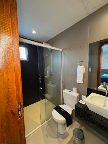a bathroom with a shower and a toilet and a sink at Hotel Califórnia in Canindé