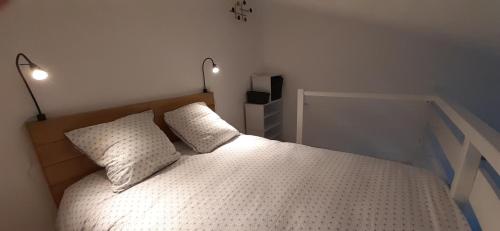 a bedroom with a bed with two pillows and two lights at La Louvatière 28 in Mijoux